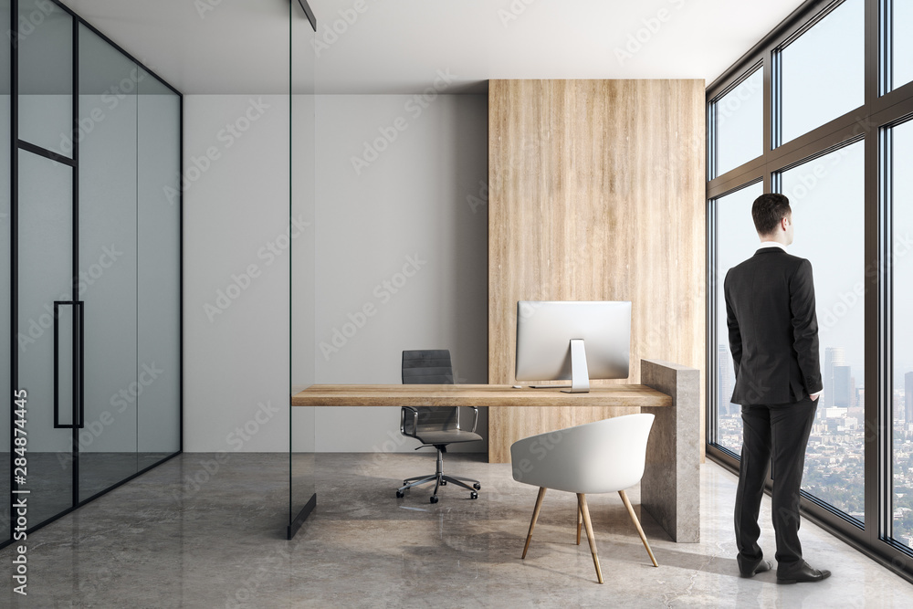 Businessman in modern office with concrete floor and wooden table.