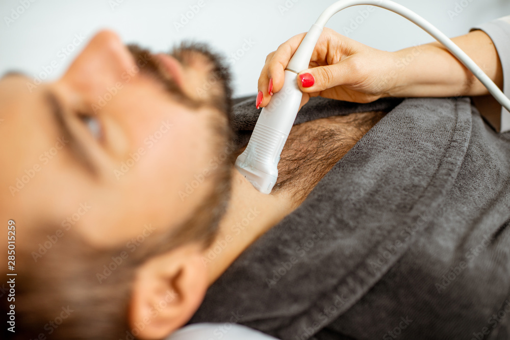 Men examining his thyroid with ultrasound