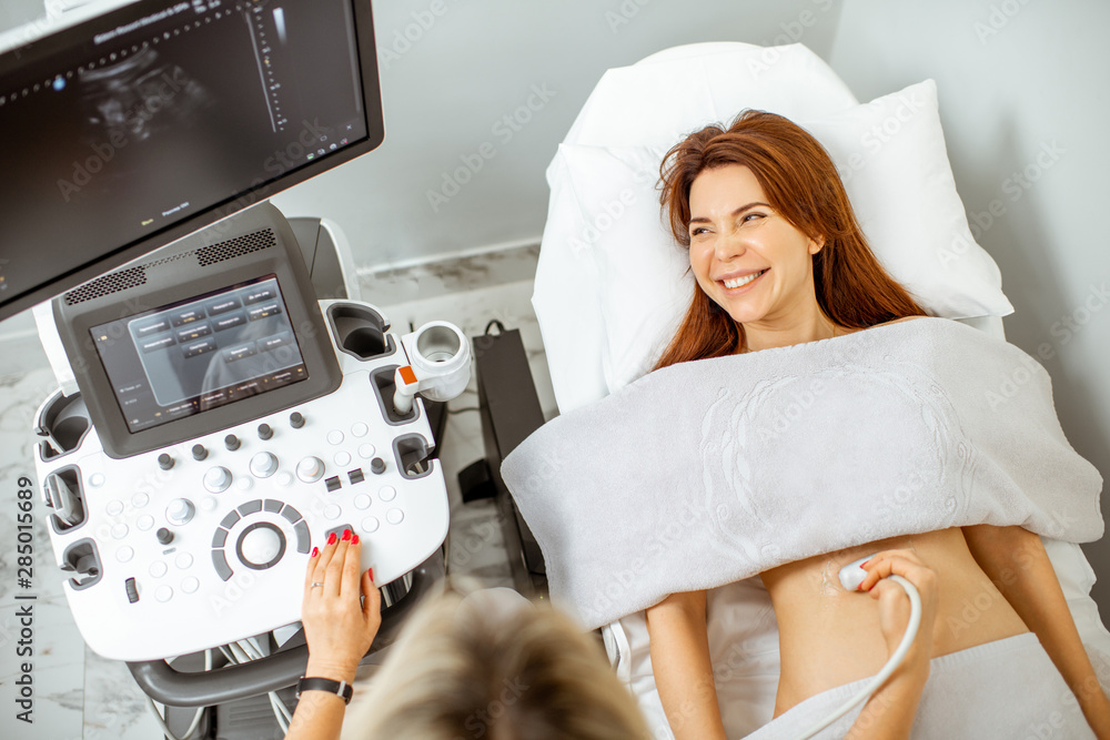 Woman examining her abdomen with ultrasound