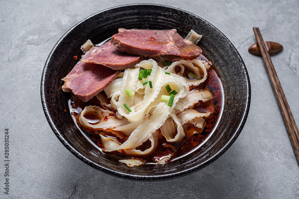 A bowl of nutritious and delicious beef noodles with noodles on a cement texture background