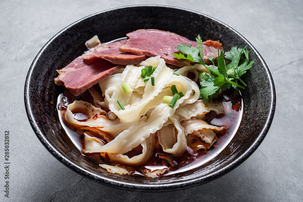 A bowl of nutritious and delicious beef noodles with noodles on a cement texture background