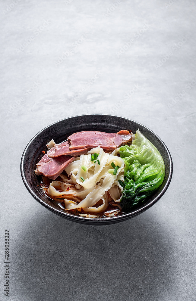 A bowl of nutritious and delicious beef noodles with noodles on a cement texture background