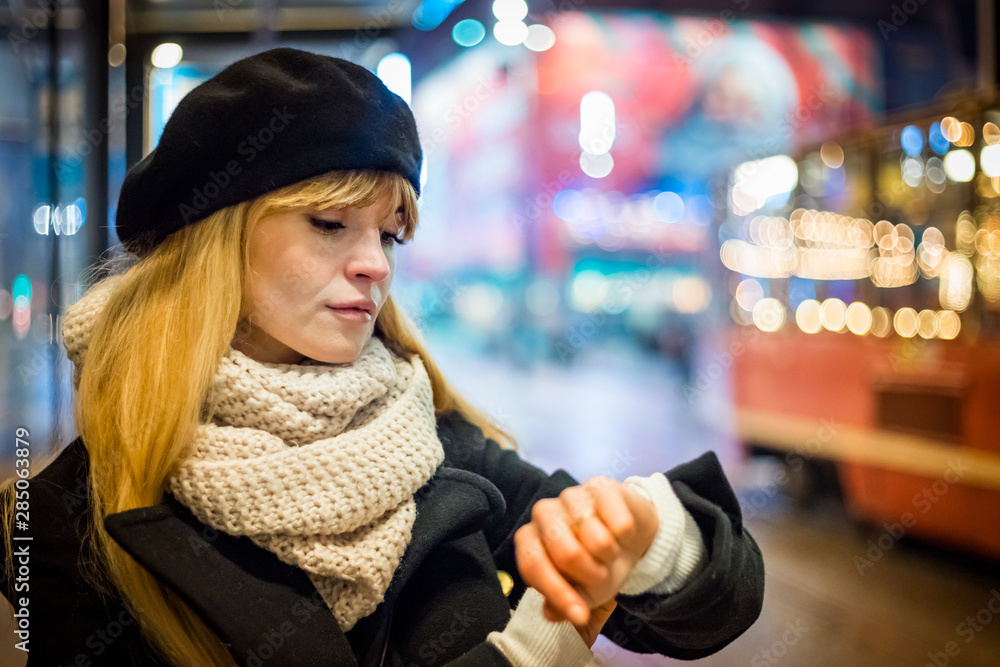 Young woman in the night city waiting at bus stop