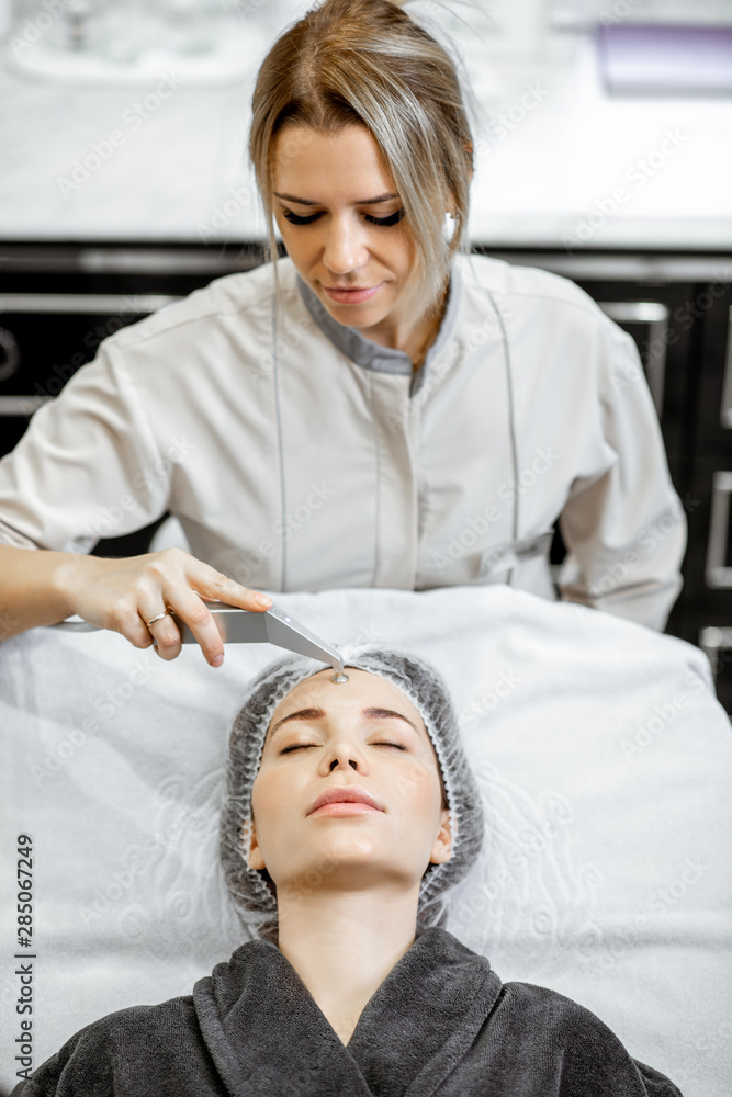 Female cosmetologist making vacuum hydro peeling to a woman at the luxury beauty salon. Concept of a