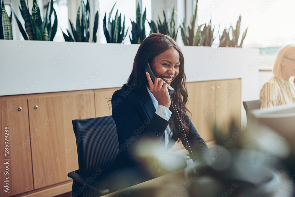 African American businesswomen talking on an office telephone an