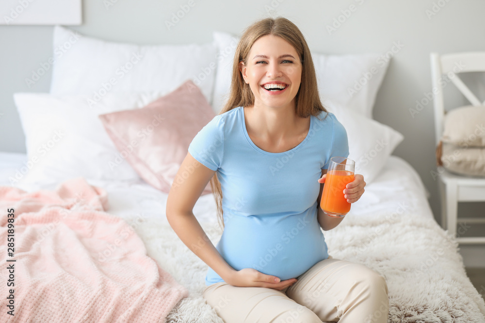 Beautiful pregnant woman drinking juice at home