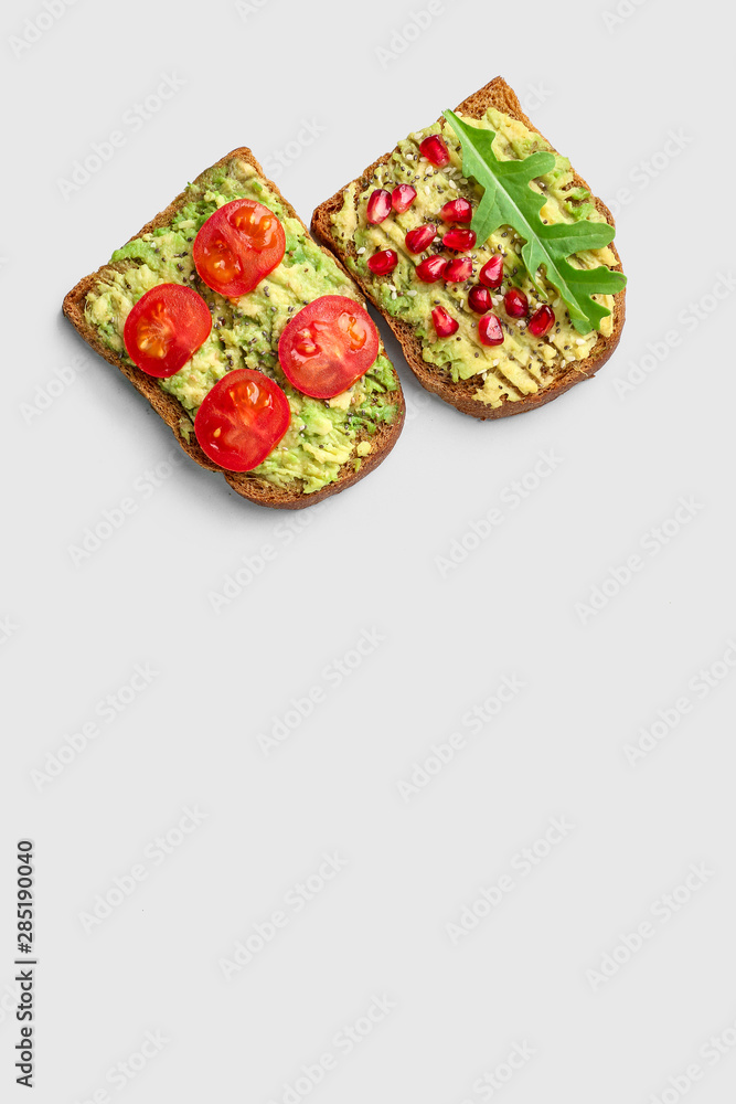 Different tasty avocado toasts on grey background