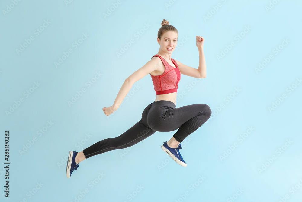 Jumping sporty woman on light color background