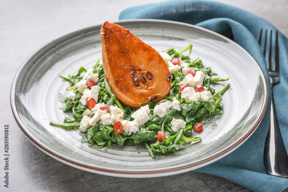 Plate with tasty arugula salad and pear on table