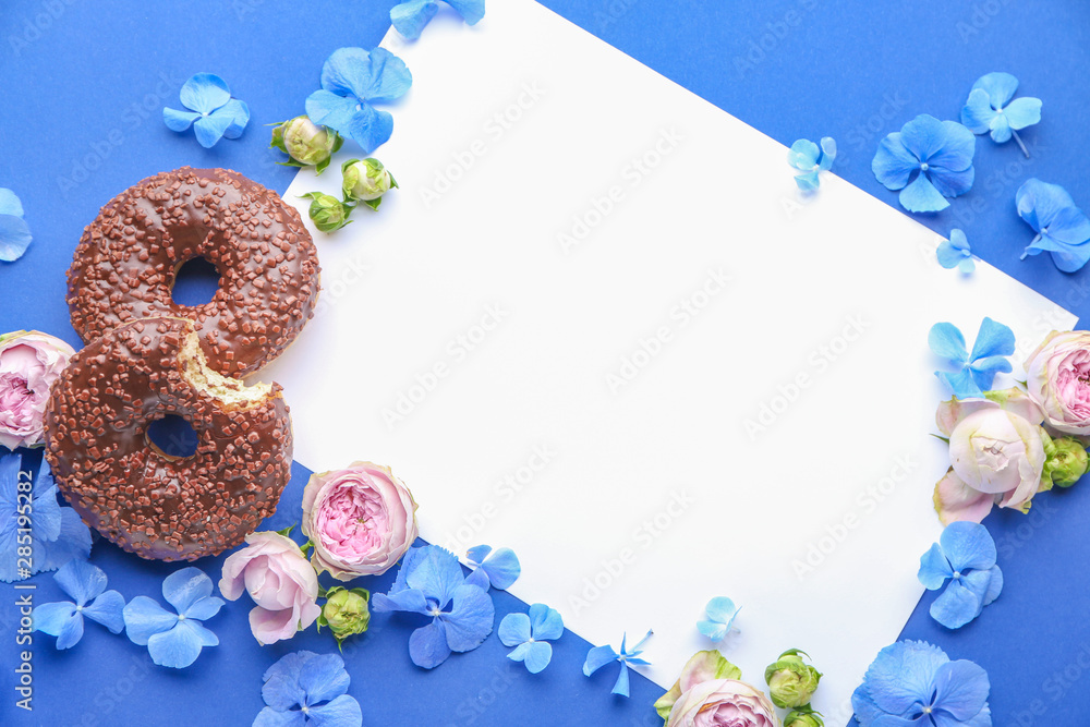 Composition with sweet tasty donuts, blank card and flowers on color background