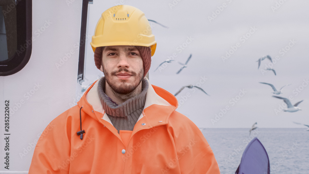 Portrait of Dressed in Bright Protective Coat Serious Fisherman on Commercial Fishing Boat  Looking 