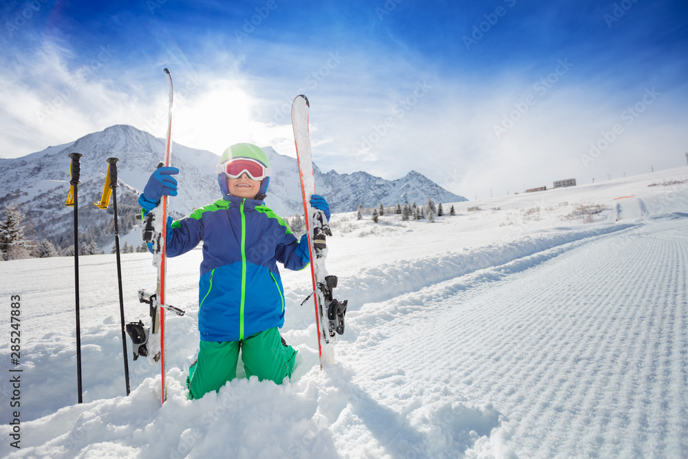 一个男孩坐在雪地里，滑雪在斜坡上的肖像