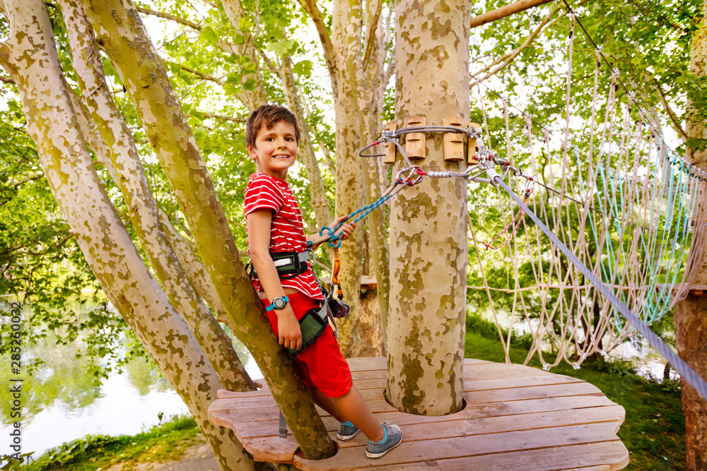 Little boy waits on tree platform at rope park