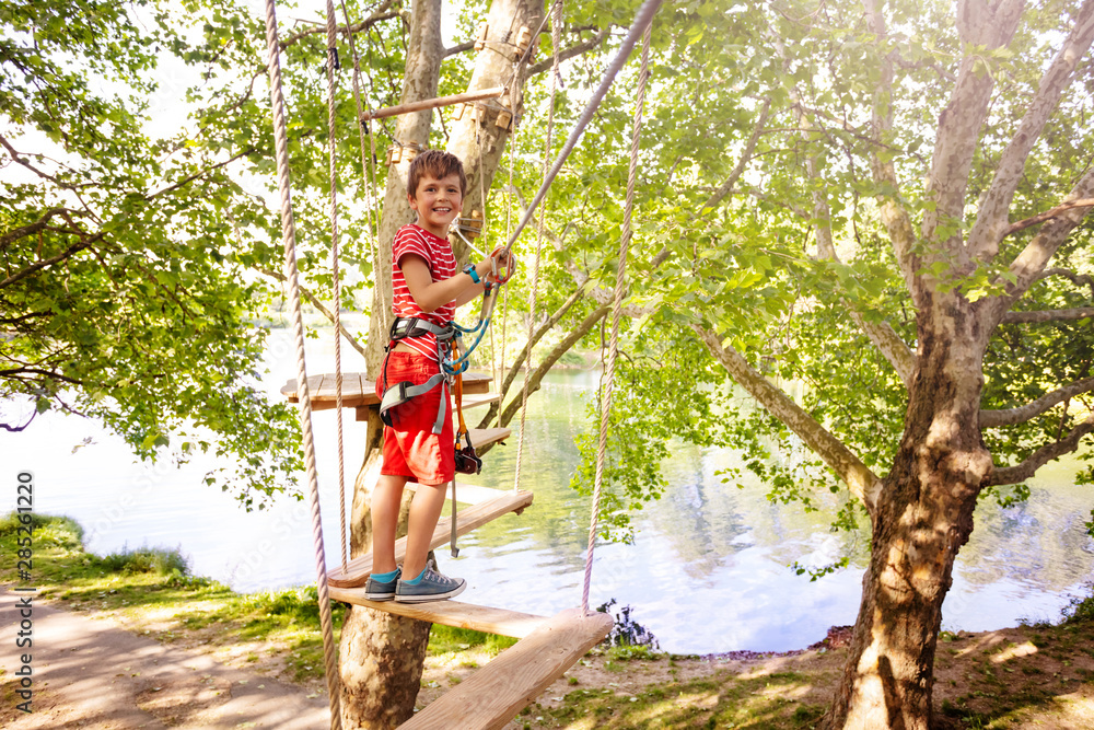 Happy boy have fun on rope walk at adventure park