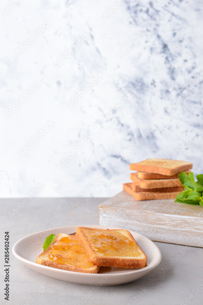 Plate with tasty toasted bread and jam on grey table