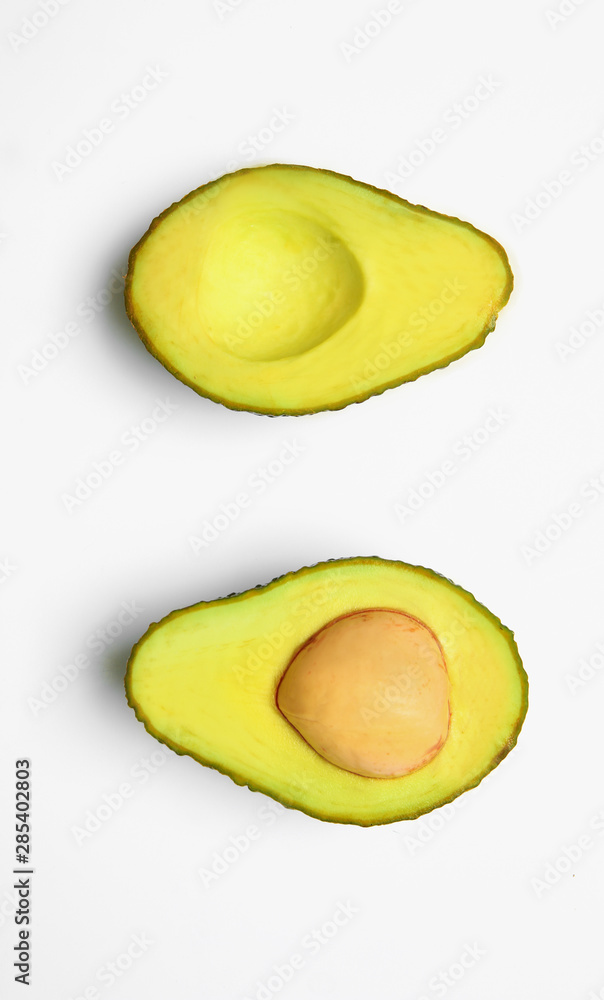 Halves of ripe avocado on white background