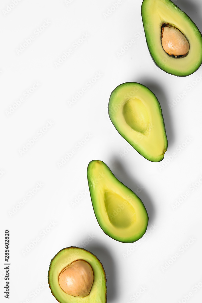 Halves of ripe avocado on white background