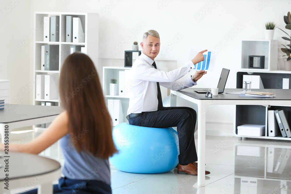 Young business people sitting on fitballs while working in office