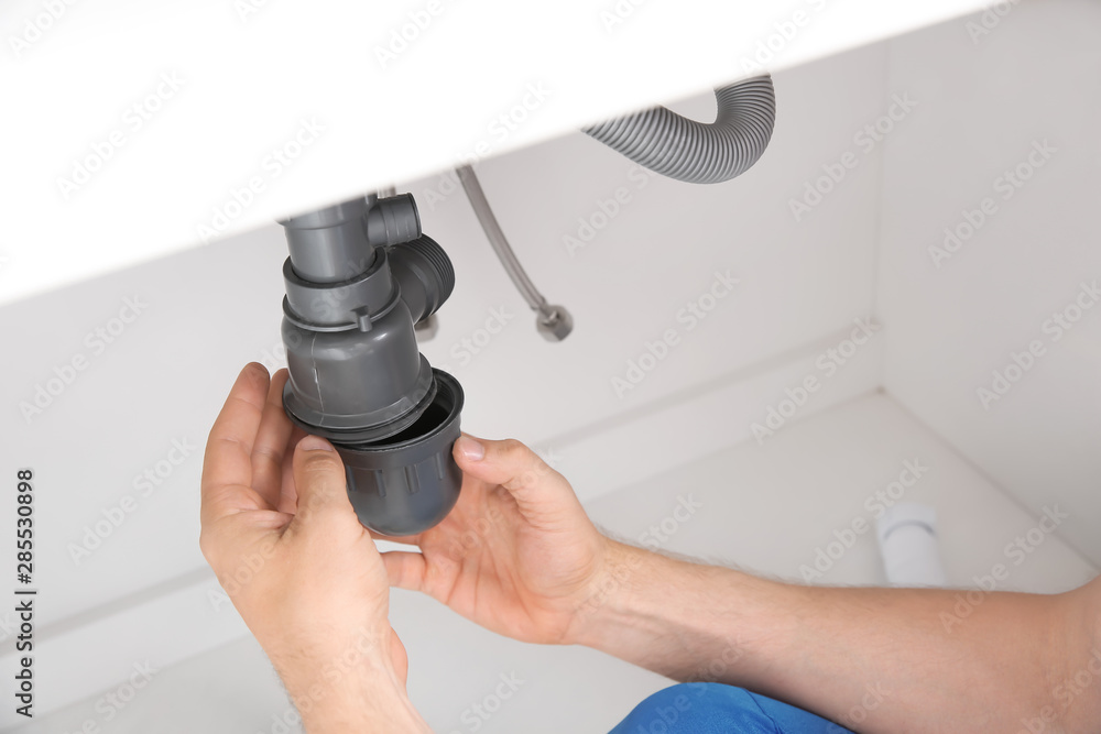 Plumber repairing pipes in kitchen