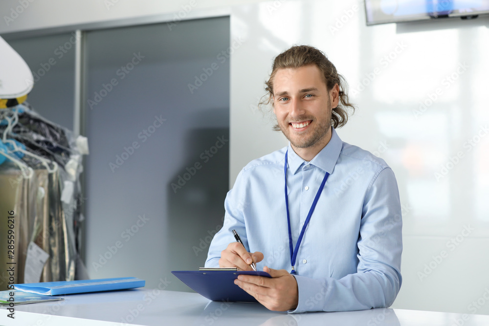 Worker of modern dry-cleaners at reception