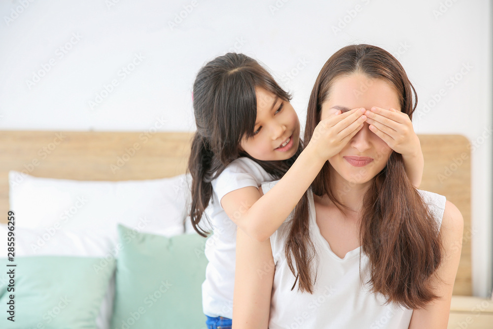 小女孩在卧室里遮住妈妈的眼睛