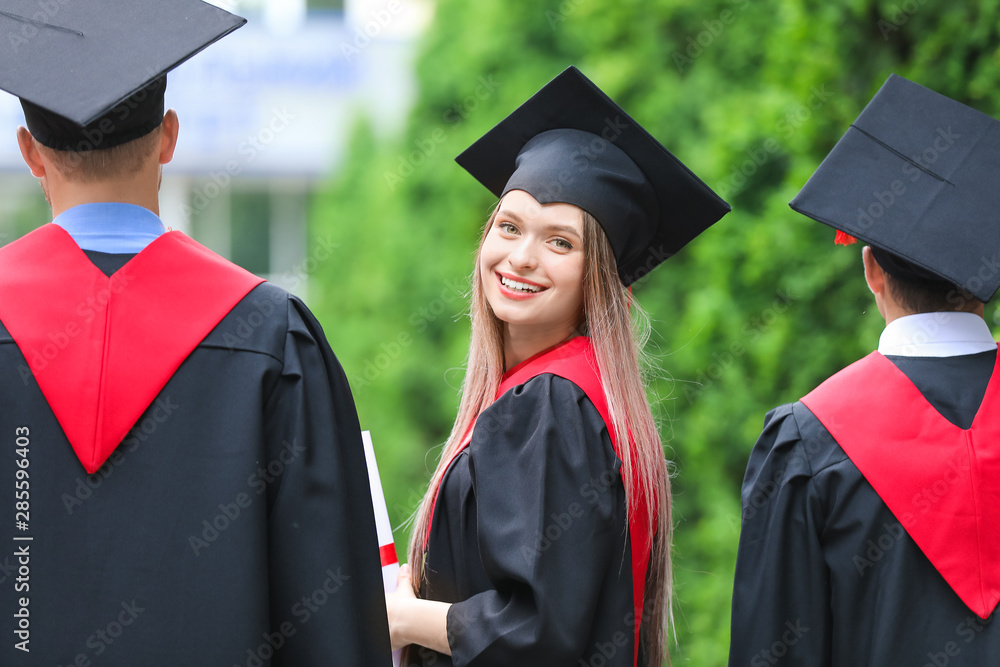 户外穿着学士袍的年轻学生