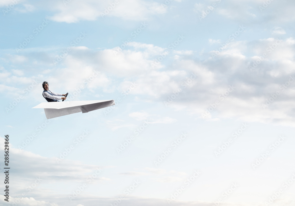 Businessman in aviator hat sitting in paper plane