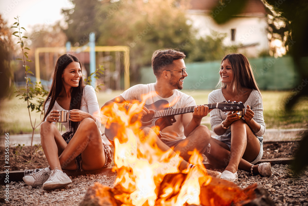 Group of young people having fun around the fire in countryside.