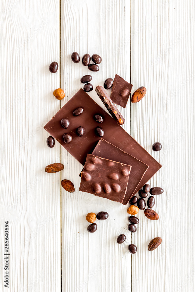 Chocolate with nuts and its ingredients on white wooden background top view