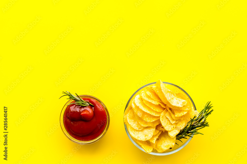 Homemade potato chips with ketchup for snack on yellow background top view copyspace