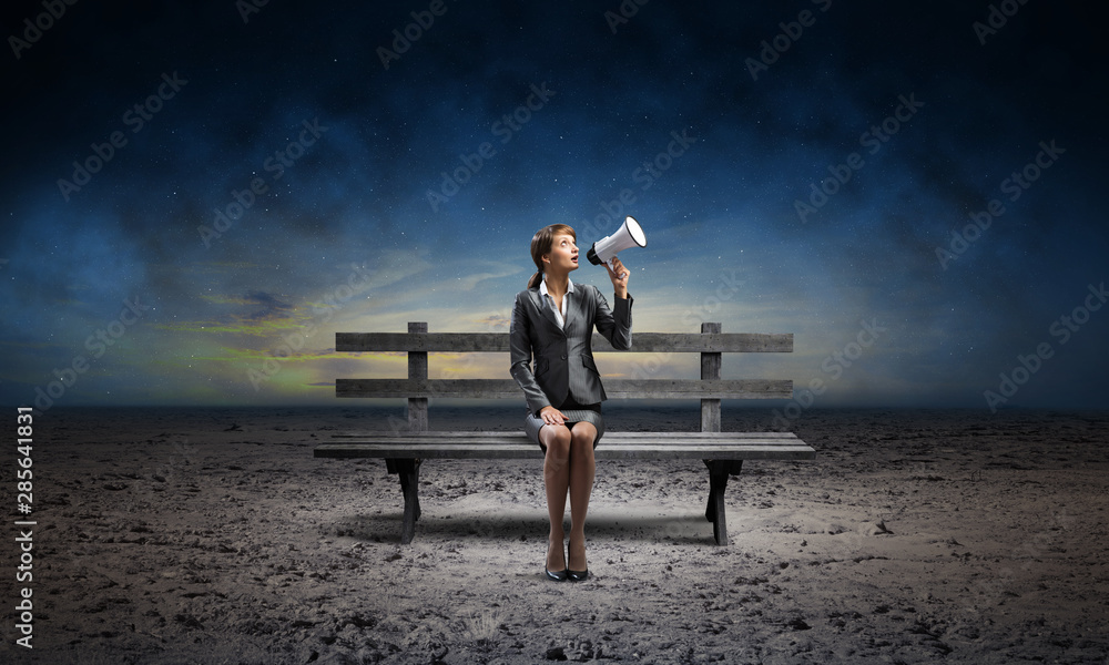 Business woman with megaphone on wooden bench