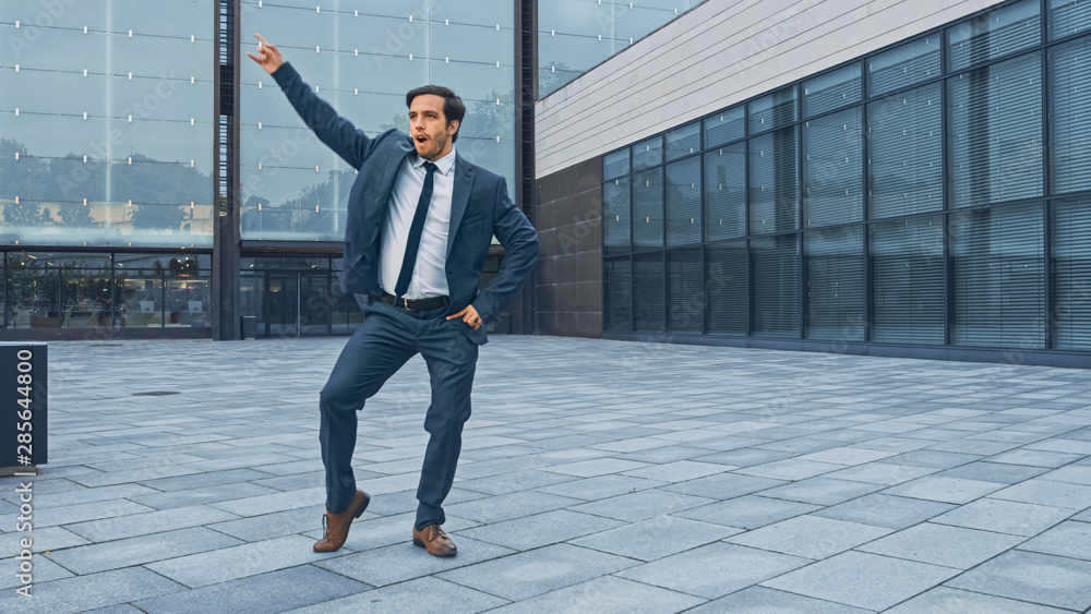 Cheerful and Happy Businessman in a Suit is Actively Dancing on a Street Square. Scene Shot in an Ur