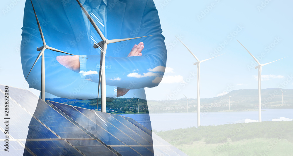 Double exposure graphic of business people working over wind turbine farm and green renewable energy