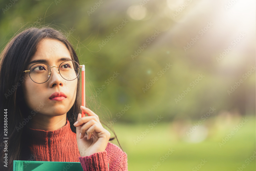 Young creative student girl thinking or planning future education while holding pencil in hand. Crea