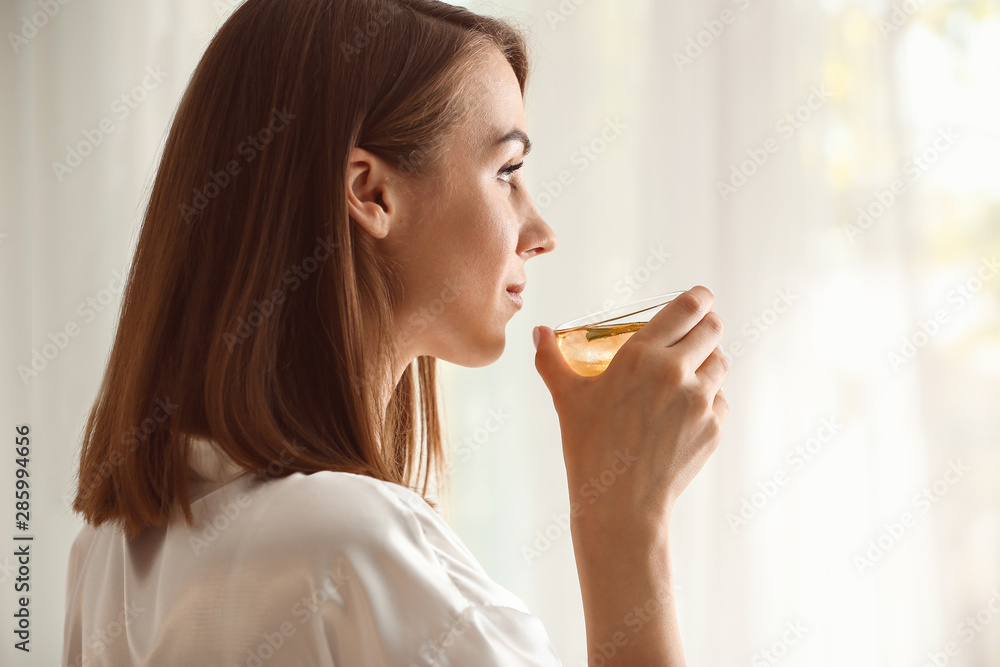 Beautiful young woman drinking tea at home