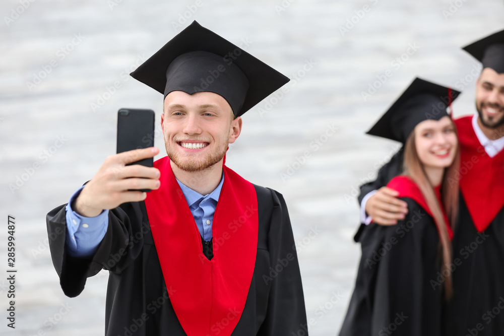 穿着学士袍的快乐学生在户外自拍