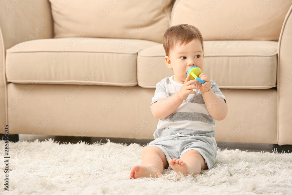 Cute little boy with nibbler sitting on floor at home