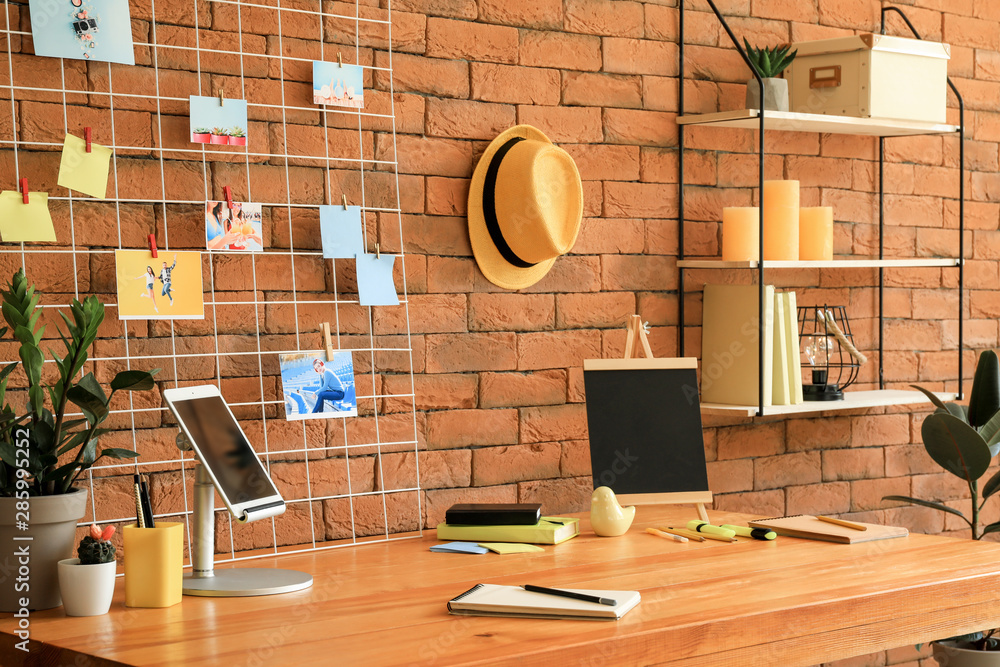 Workplace with mood board near brick wall in modern room