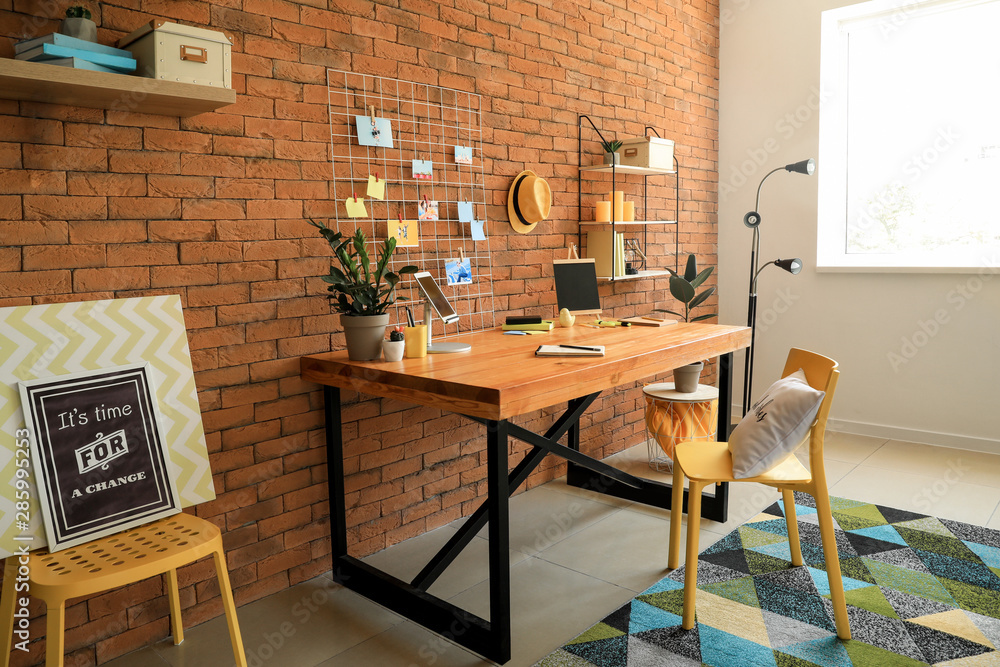 Workplace with mood board near brick wall in modern room