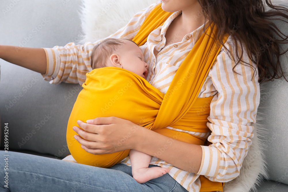 Young mother with little baby in sling at home