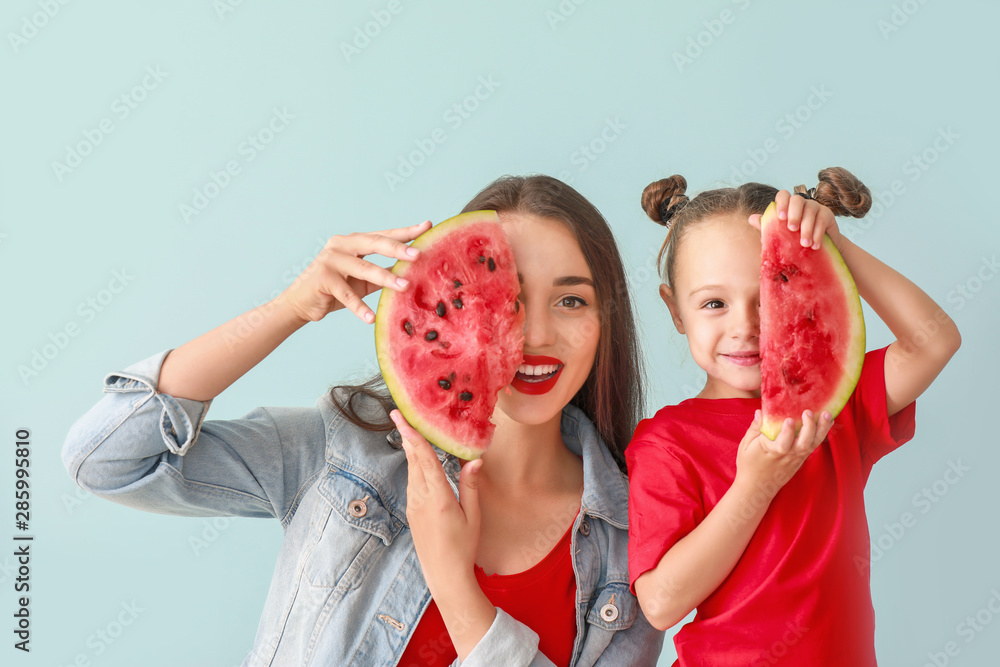 Beautiful young woman and cute girl with fresh watermelon on color background