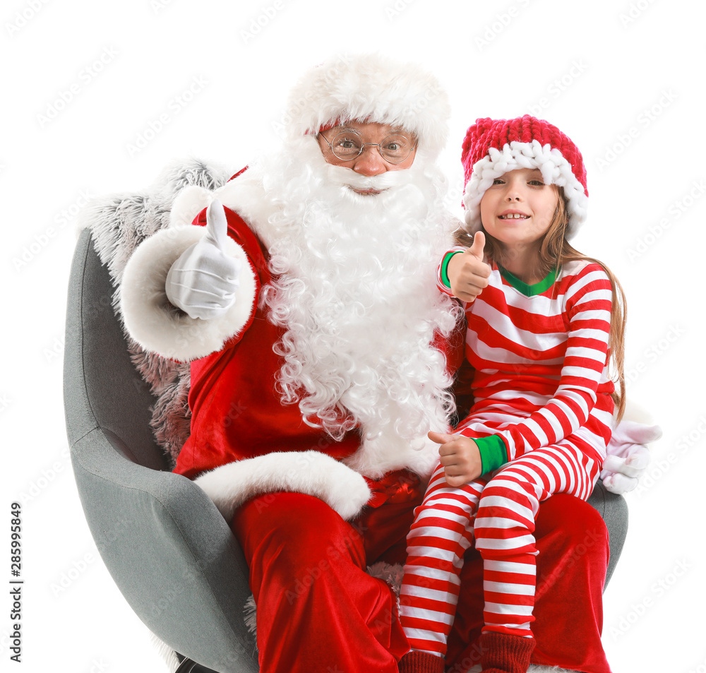 Santa Claus and little girl showing thumb-up while sitting in armchair against white background