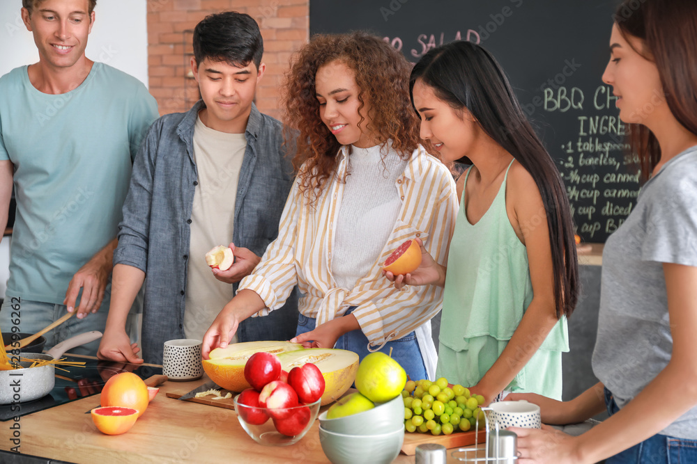 Happy friends cooking together in kitchen