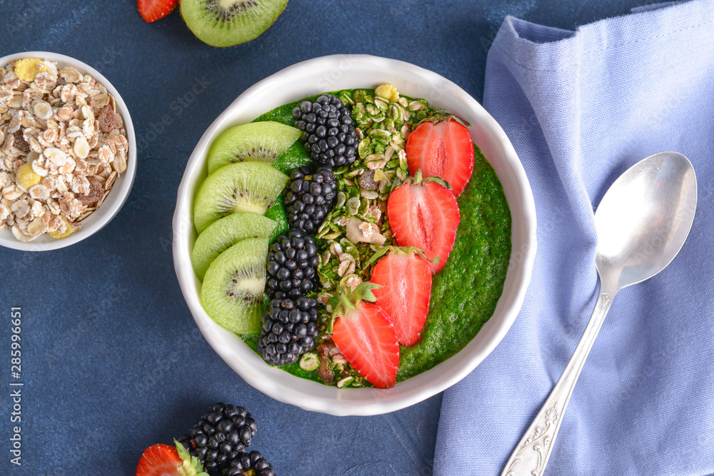 Bowl with tasty oat flakes, spirulina, berries and kiwi on table