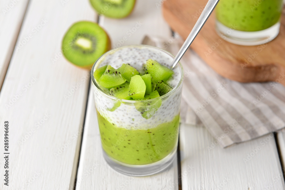 Glass with tasty kiwi dessert on white table