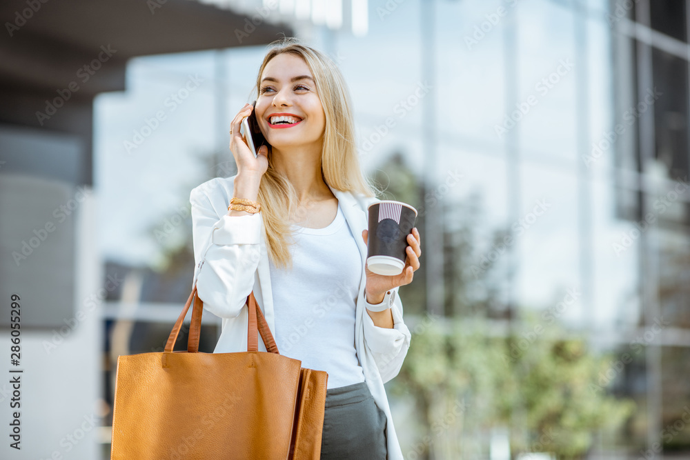 Portrait of a young businesswoman talking with phone during a coffee break near the office building 