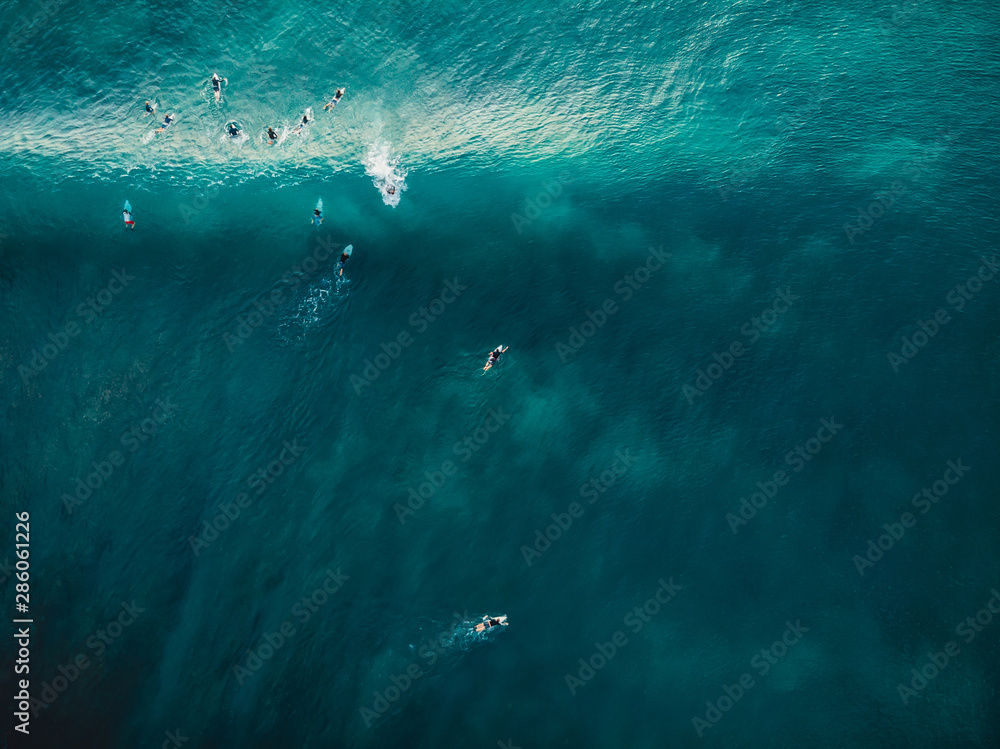 Aerial view with surfers and barrel wave in tropical blue ocean. Top view