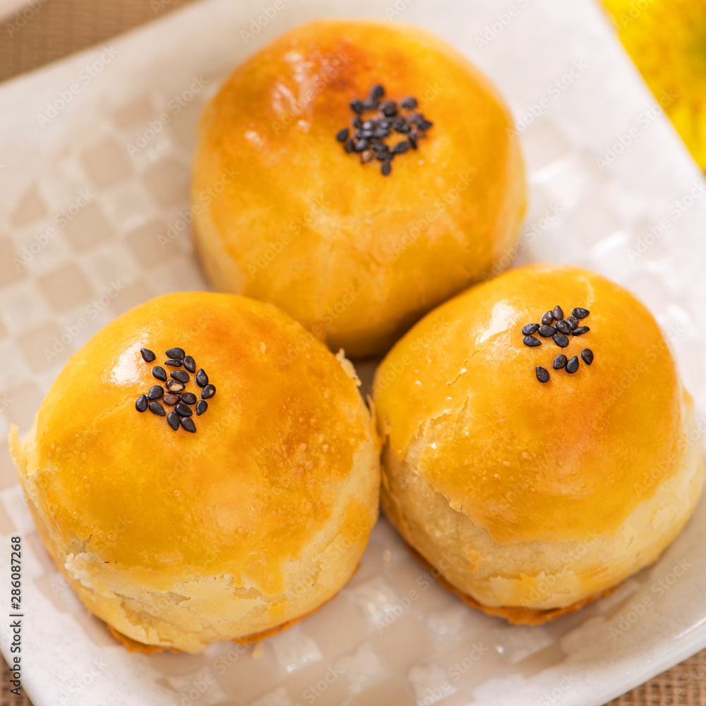 Tasty baked egg yolk pastry moon cake for Mid-Autumn Festival on bright wooden table background. Chi