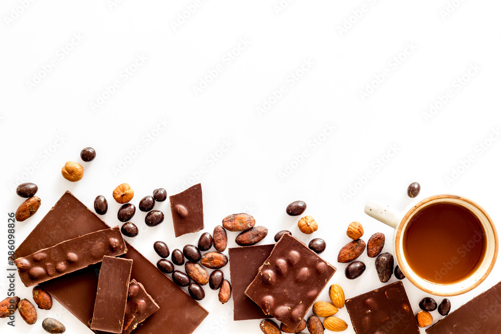 Chocolate bars and nuts on white table background top view mockup