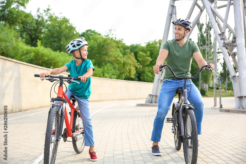 Happy father and son riding bicycles outdoors